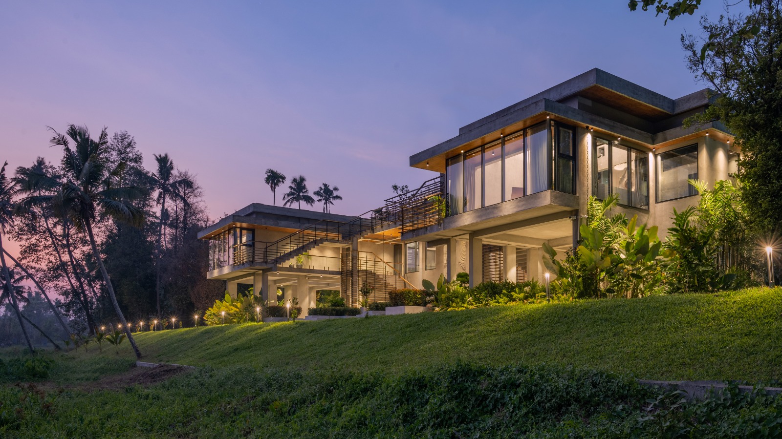 Sovnear private estate at dusk — illuminated architecture set in Kerala's tropical landscape