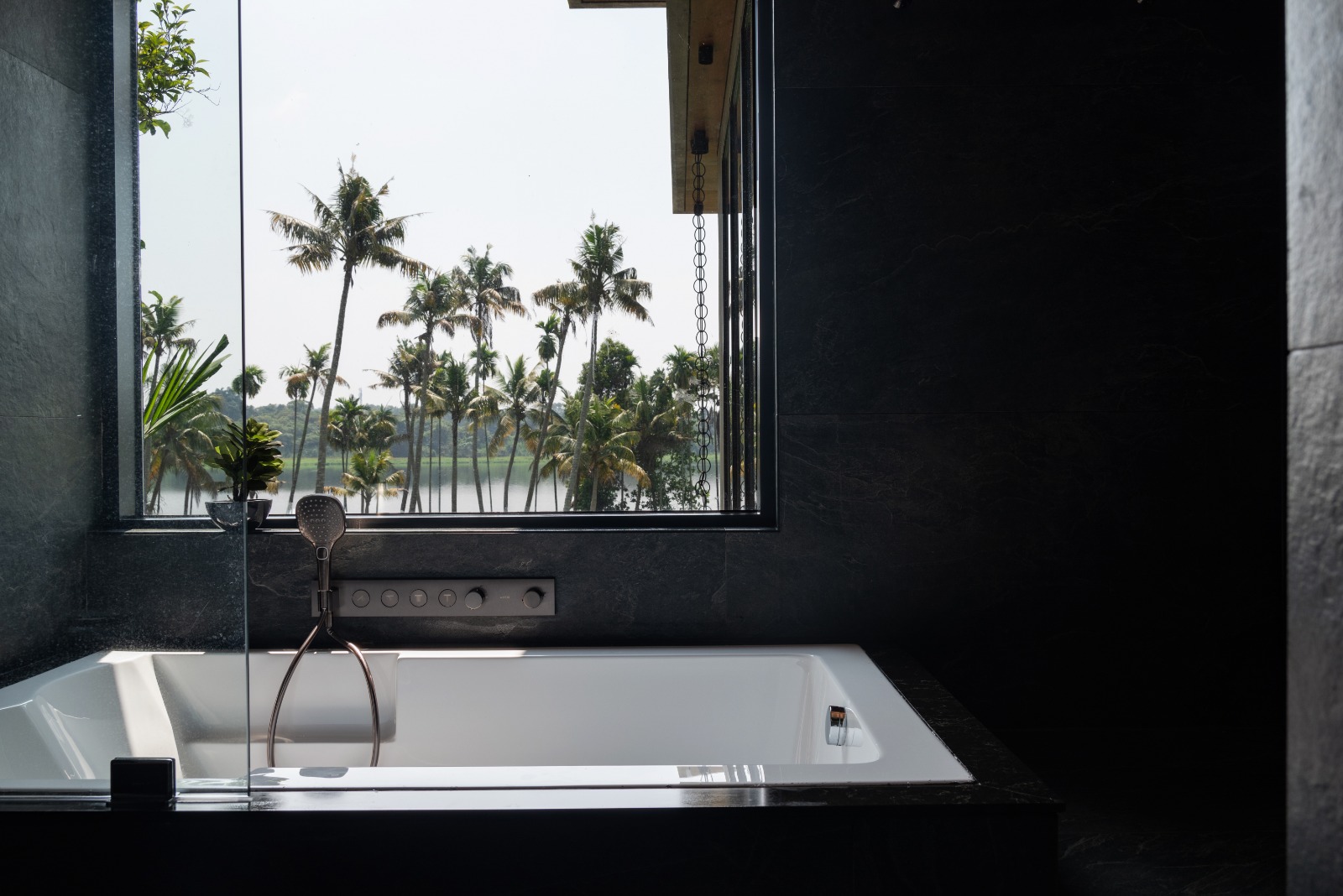 Sovnear luxury bathroom — deep soaking bath overlooking Kerala backwaters and palms