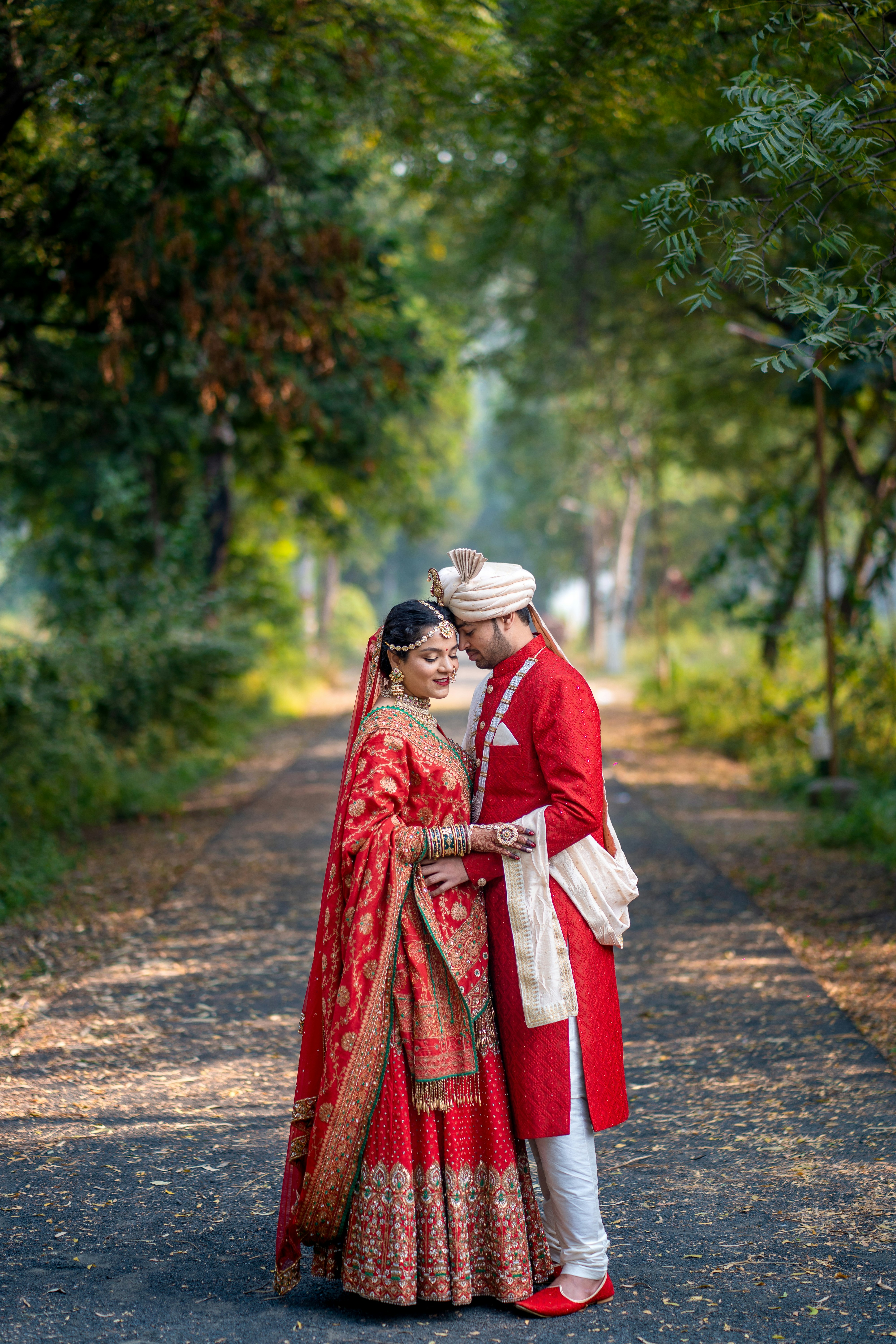 Wedding couple sharing an intimate moment on a sunlit forest path